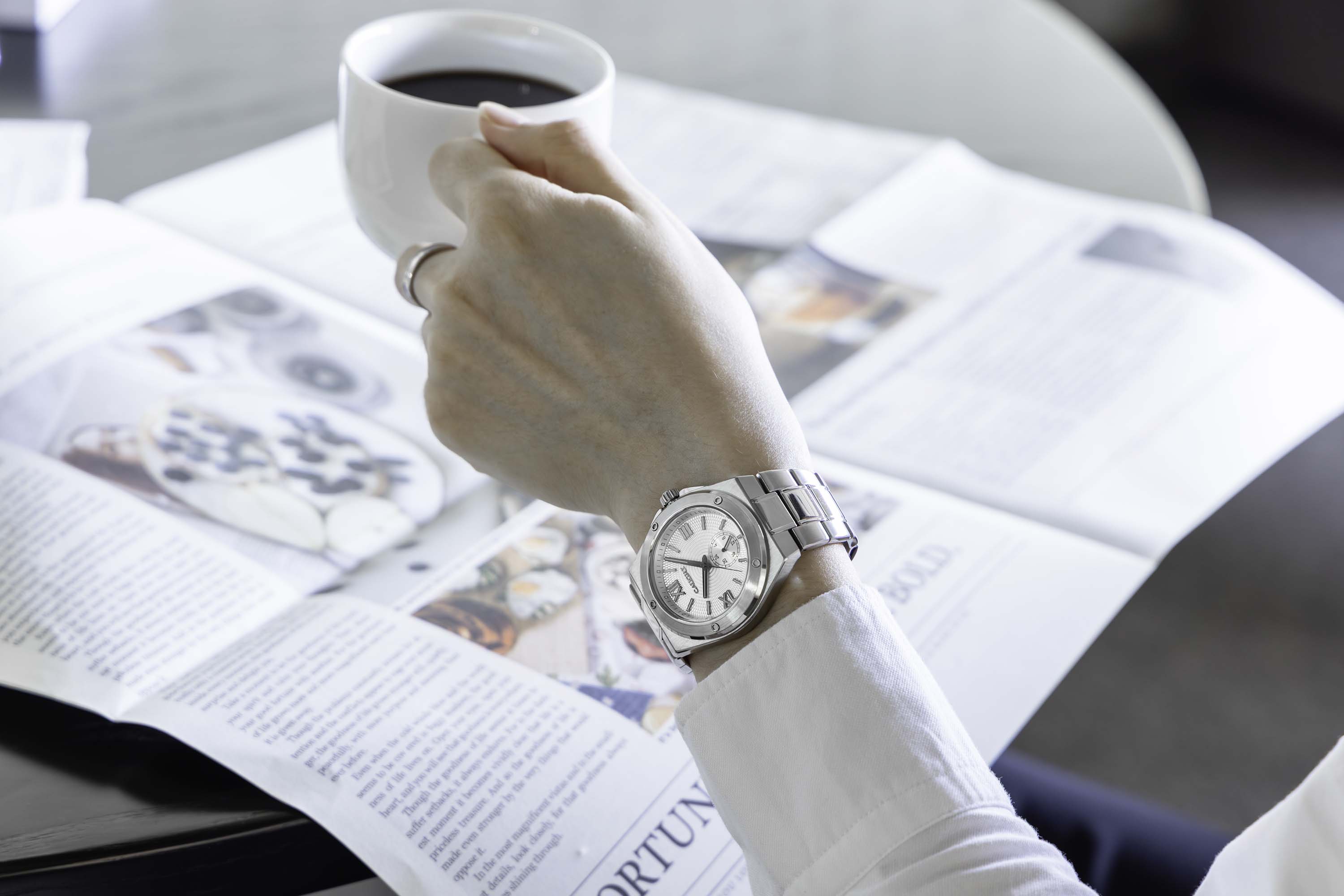 The wear display of Pillarix watch with white dial in a casual coffee drinking scene.