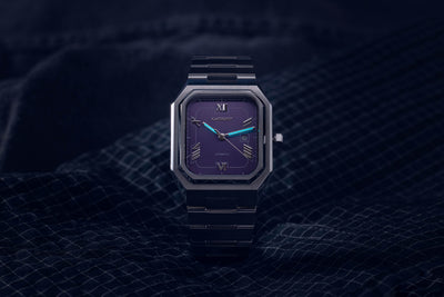 Monarch purple dial automatic watch displaying luminous hands and markers in low light conditions