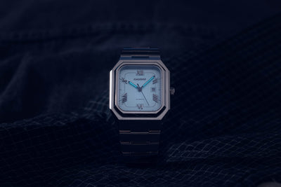 Monarch baby blue dial automatic watch displaying luminous hands and markers in low light conditions