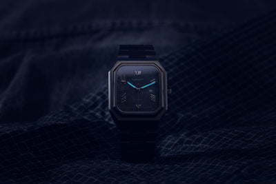 Monarch carbon black dial automatic watch displaying luminous hands and markers in low light conditions